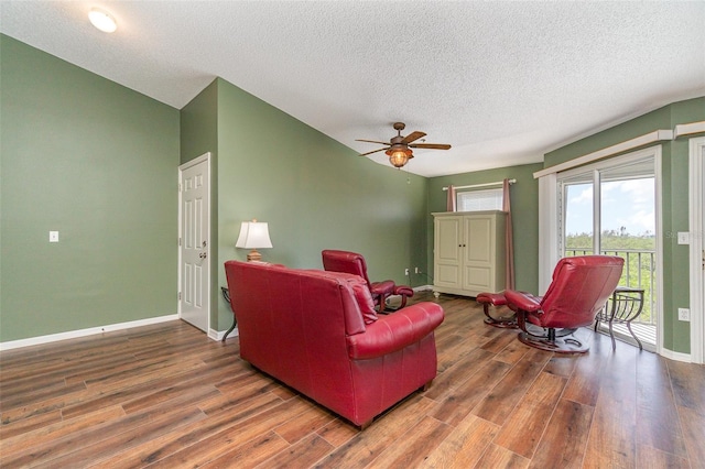 living room with a textured ceiling, dark hardwood / wood-style flooring, and ceiling fan