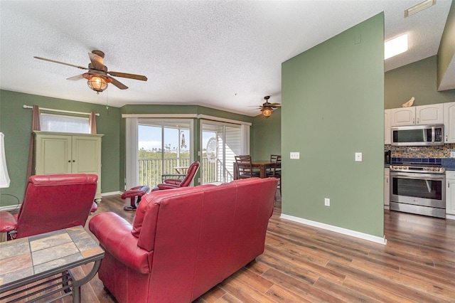 living room with a textured ceiling, dark hardwood / wood-style floors, and ceiling fan