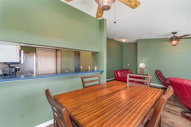 dining area with a textured ceiling and light wood-type flooring