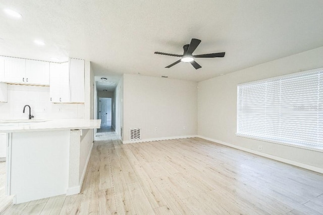 unfurnished living room with ceiling fan, sink, and light hardwood / wood-style flooring