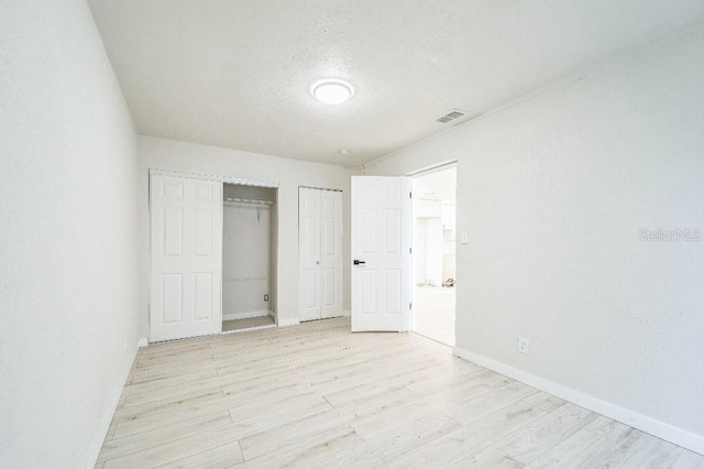 unfurnished bedroom featuring a textured ceiling, light hardwood / wood-style flooring, and a closet