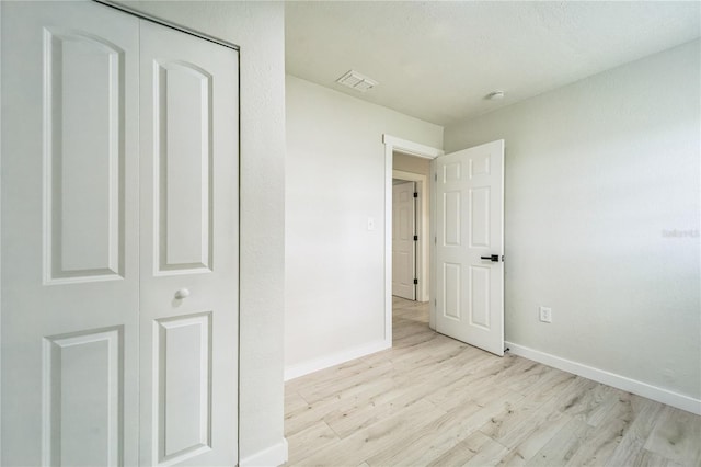 unfurnished bedroom featuring light wood-type flooring and a closet