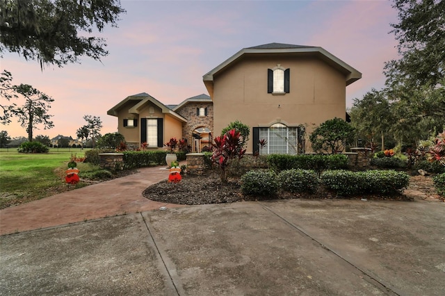 12709 Mannhurst Oak Ln, Lithia, FL 33547 - view of front of house with stucco siding, a front yard, and stone siding