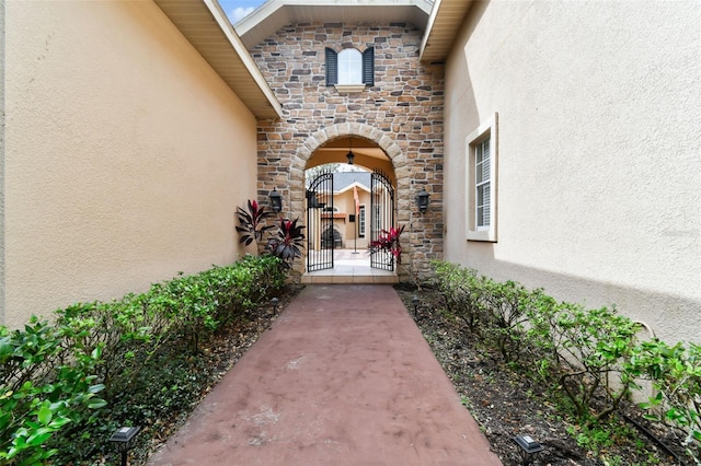 property entrance featuring stone siding, a gate, and stucco siding