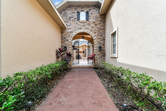 12709 Mannhurst Oak Ln, Lithia, FL 33547 - view of exterior entry featuring stucco siding, stone siding, and a gate