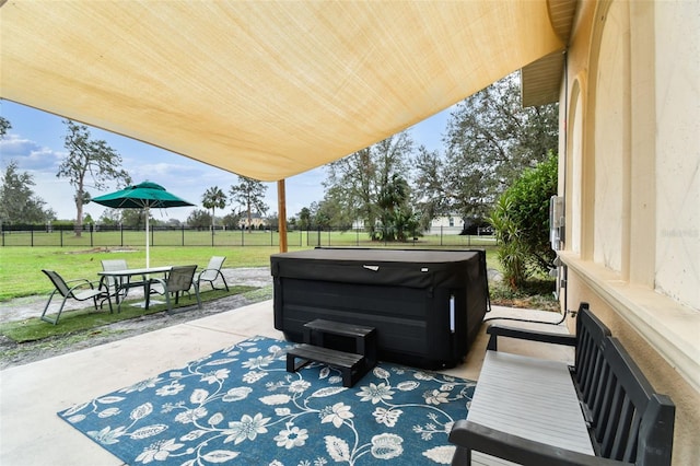 view of patio featuring outdoor dining area, fence, and a hot tub