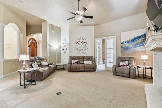 living area featuring light carpet, arched walkways, ceiling fan, french doors, and ornate columns