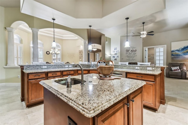 kitchen with pendant lighting, a center island with sink, brown cabinetry, open floor plan, and a sink