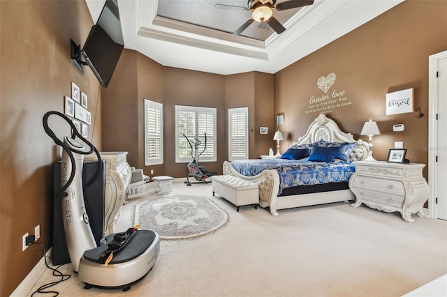 carpeted bedroom with a ceiling fan, a tray ceiling, crown molding, and baseboards