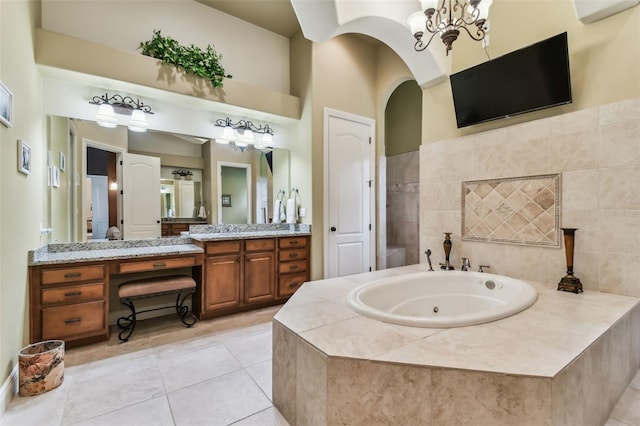 bathroom with tile patterned flooring, vanity, a whirlpool tub, and an inviting chandelier