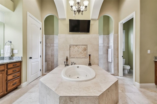 bathroom featuring vanity, a relaxing tiled tub, a notable chandelier, tile patterned flooring, and toilet