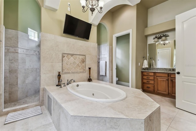 bathroom featuring a garden tub, vanity, a walk in shower, a chandelier, and tile patterned flooring