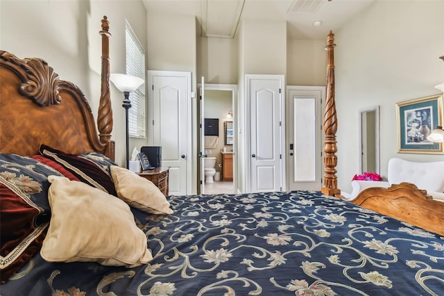 bedroom with ensuite bath, a high ceiling, and visible vents