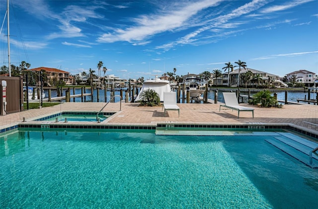 view of pool with a boat dock, a water view, and a hot tub