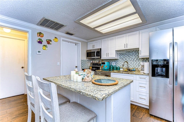 kitchen featuring crown molding, dark hardwood / wood-style flooring, white cabinets, and stainless steel appliances