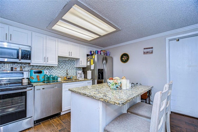 kitchen featuring white cabinets, stainless steel appliances, a kitchen island, and dark wood-type flooring