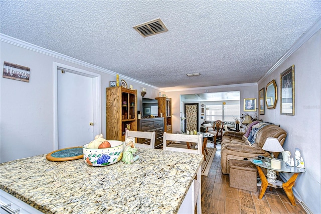 dining room with wood-type flooring, a textured ceiling, and crown molding