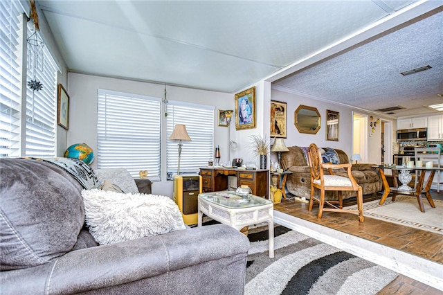 living room with hardwood / wood-style floors, crown molding, and a textured ceiling