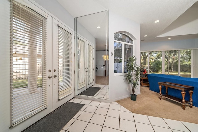 foyer entrance featuring a healthy amount of sunlight, light colored carpet, and a textured ceiling