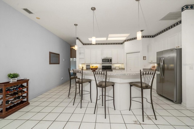 kitchen featuring white cabinetry, hanging light fixtures, stainless steel appliances, and light stone counters