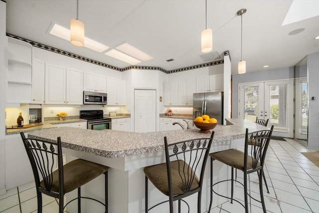 kitchen featuring a kitchen breakfast bar, white cabinets, pendant lighting, and appliances with stainless steel finishes