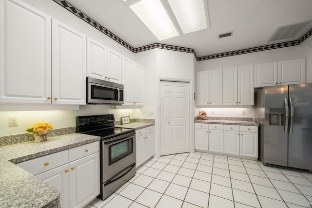 kitchen featuring light tile patterned flooring, white cabinets, and stainless steel appliances