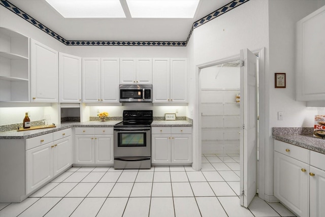 kitchen with appliances with stainless steel finishes, white cabinetry, and light tile patterned flooring