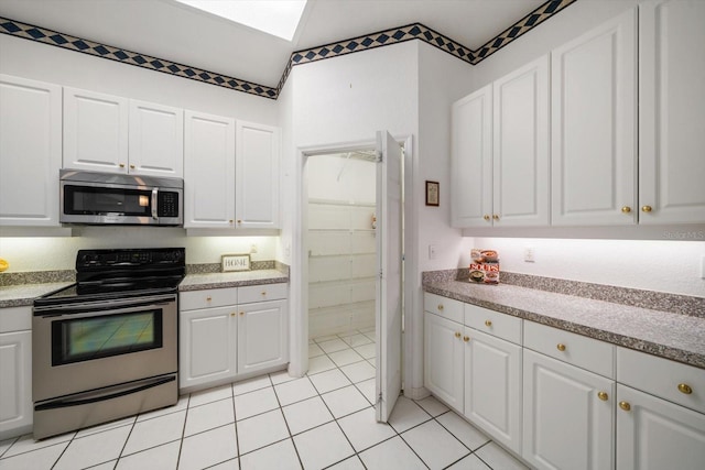 kitchen with appliances with stainless steel finishes, light tile patterned floors, and white cabinetry