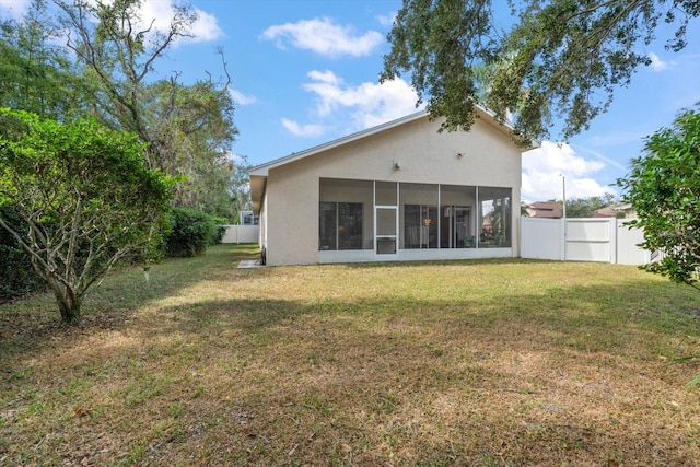 rear view of house featuring a sunroom and a yard