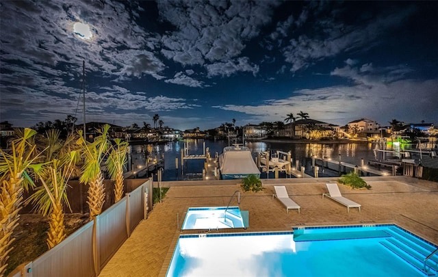 pool at dusk with a patio, a water view, and a dock