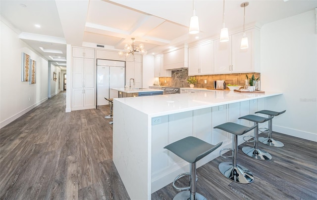 kitchen with pendant lighting, coffered ceiling, kitchen peninsula, dark hardwood / wood-style flooring, and white cabinetry