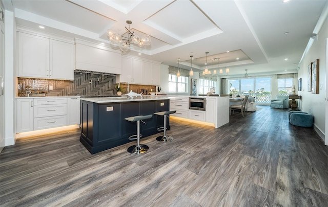 kitchen featuring white cabinets, an island with sink, and pendant lighting