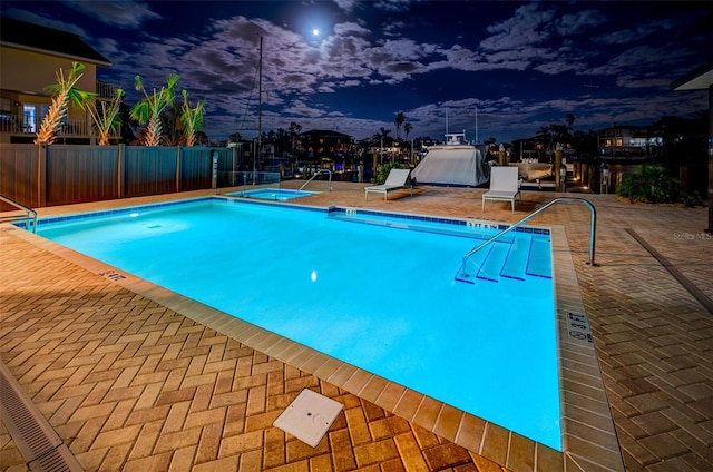 pool at dusk with a patio area