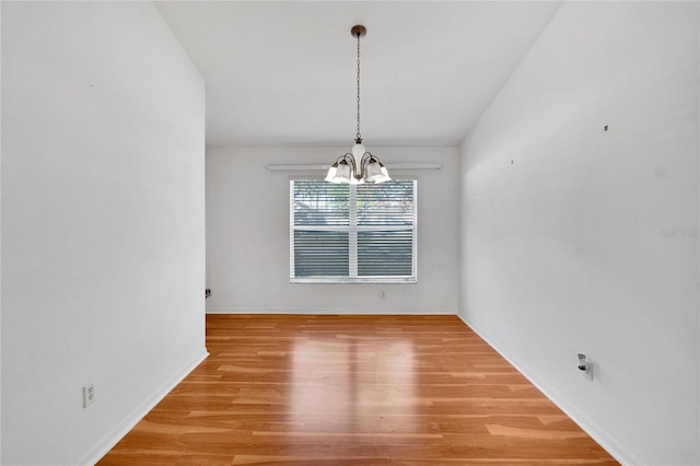 unfurnished dining area featuring a chandelier and wood-type flooring