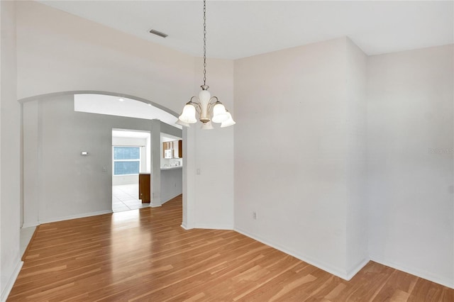 unfurnished dining area featuring light hardwood / wood-style floors and an inviting chandelier