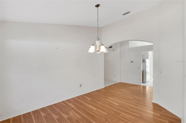 unfurnished room featuring light hardwood / wood-style floors, lofted ceiling, and an inviting chandelier