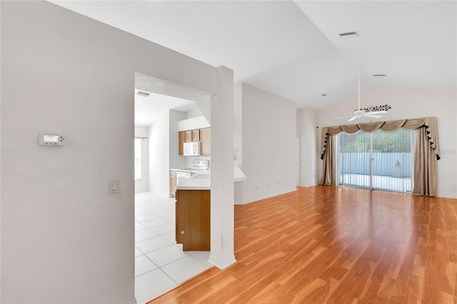 interior space with a textured ceiling, light wood-type flooring, vaulted ceiling, and ceiling fan