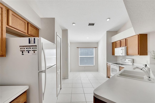 kitchen featuring a textured ceiling, white appliances, sink, and light tile patterned floors