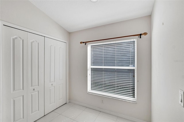 unfurnished bedroom with multiple windows, light tile patterned floors, and a closet