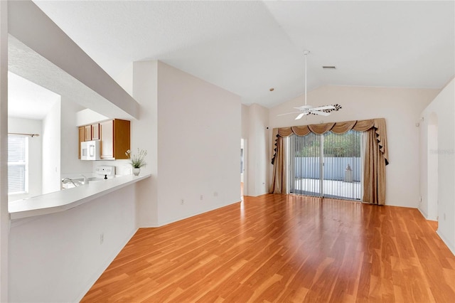 unfurnished living room with a healthy amount of sunlight, light wood-type flooring, and vaulted ceiling