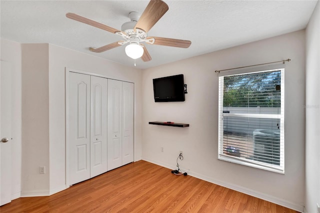 unfurnished bedroom featuring a closet, light hardwood / wood-style flooring, ceiling fan, and a textured ceiling