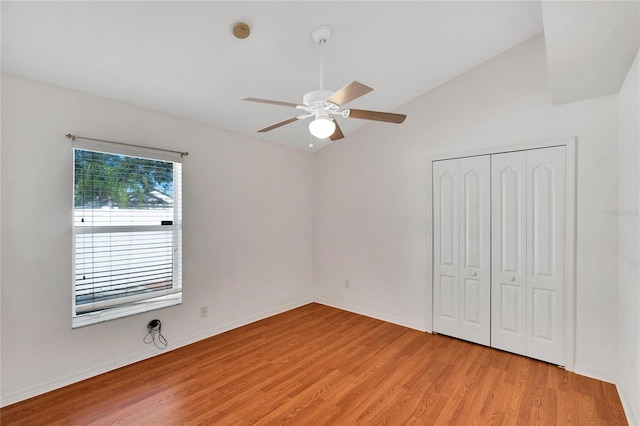 unfurnished bedroom featuring a closet, light hardwood / wood-style flooring, ceiling fan, and vaulted ceiling