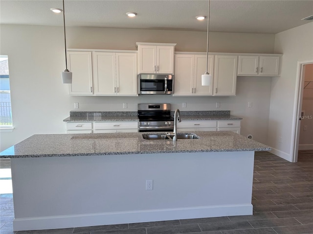 kitchen featuring stone counters, stainless steel appliances, white cabinetry, and sink