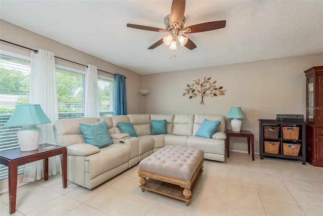 living room with ceiling fan, light tile patterned floors, and a textured ceiling