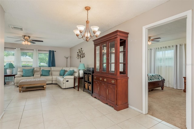 carpeted living room with ceiling fan with notable chandelier and a textured ceiling