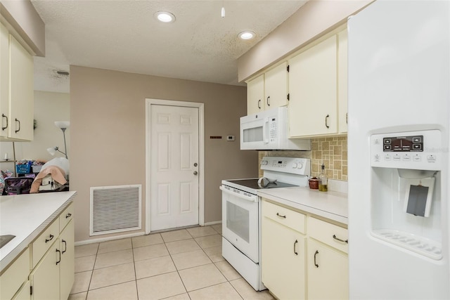 kitchen with white appliances, a textured ceiling, tasteful backsplash, cream cabinetry, and light tile patterned flooring