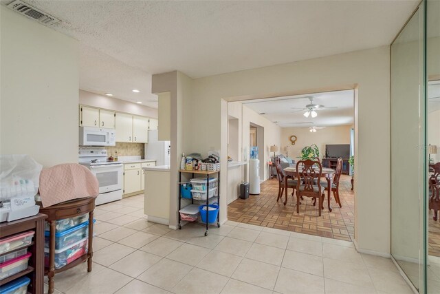 kitchen with white appliances, backsplash, ceiling fan, a textured ceiling, and white cabinetry