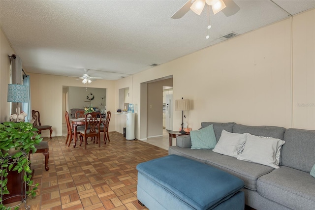 living room featuring ceiling fan, parquet floors, and a textured ceiling