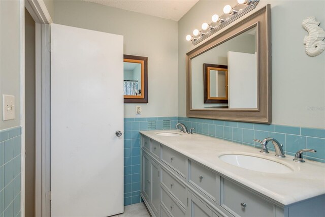 bathroom featuring a textured ceiling, vanity, and tile walls