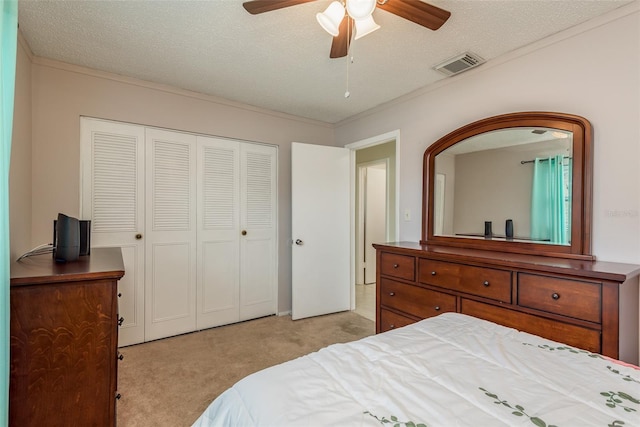 bedroom with ceiling fan, a textured ceiling, light carpet, and a closet